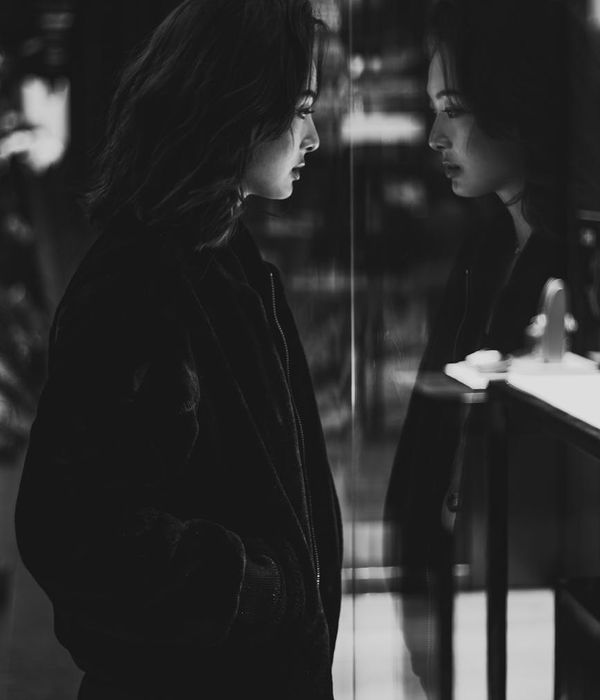 Woman performing a strength-based pose in a dark, focused environment.